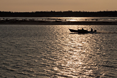  > Taxi boat on the Moose River moving through sun's reflection in front of sandbar on its way to Moose Factory.